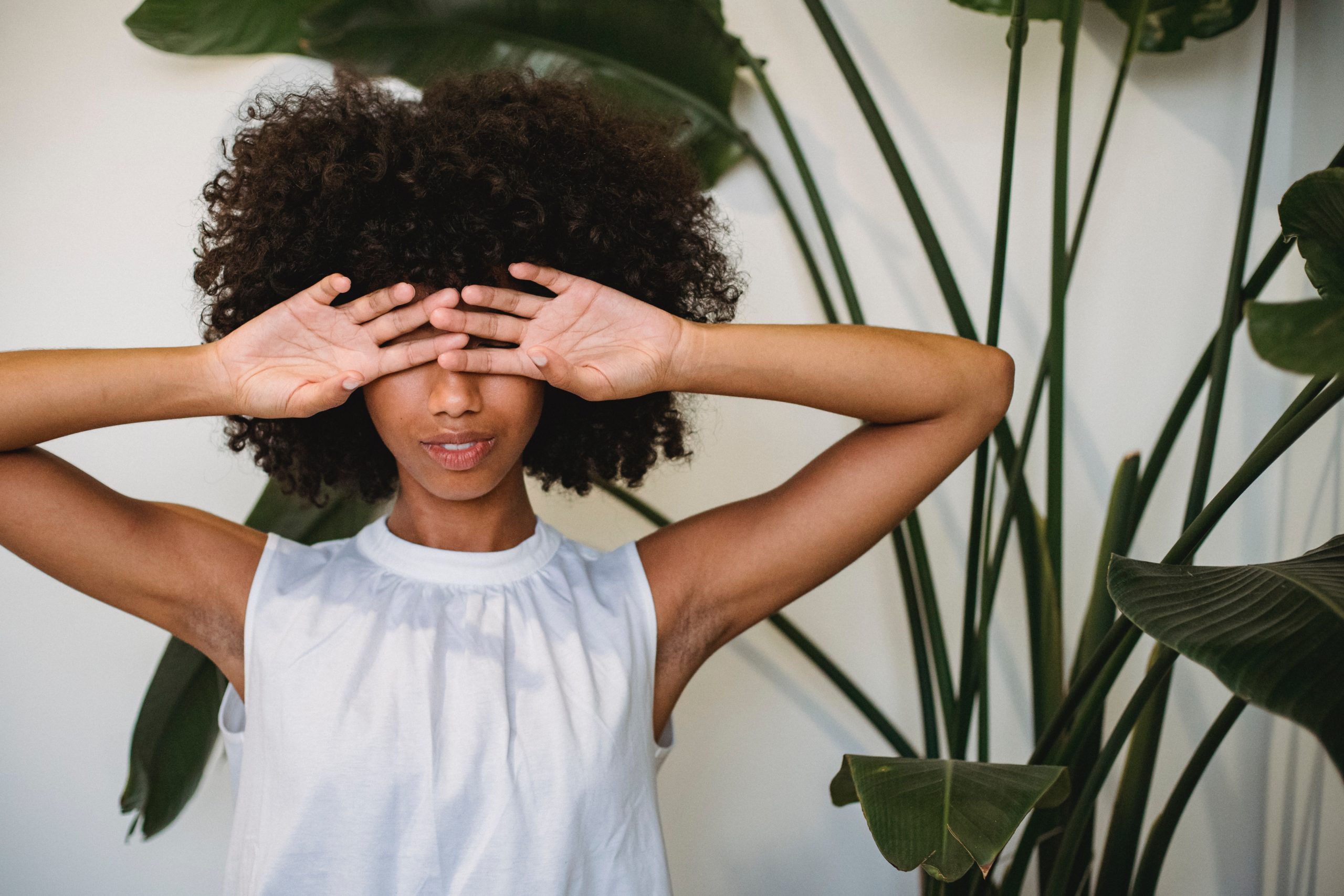 Photo by Samson Katt: https://www.pexels.com/photo/black-woman-covering-face-with-hands-standing-near-potted-plant-5255560/